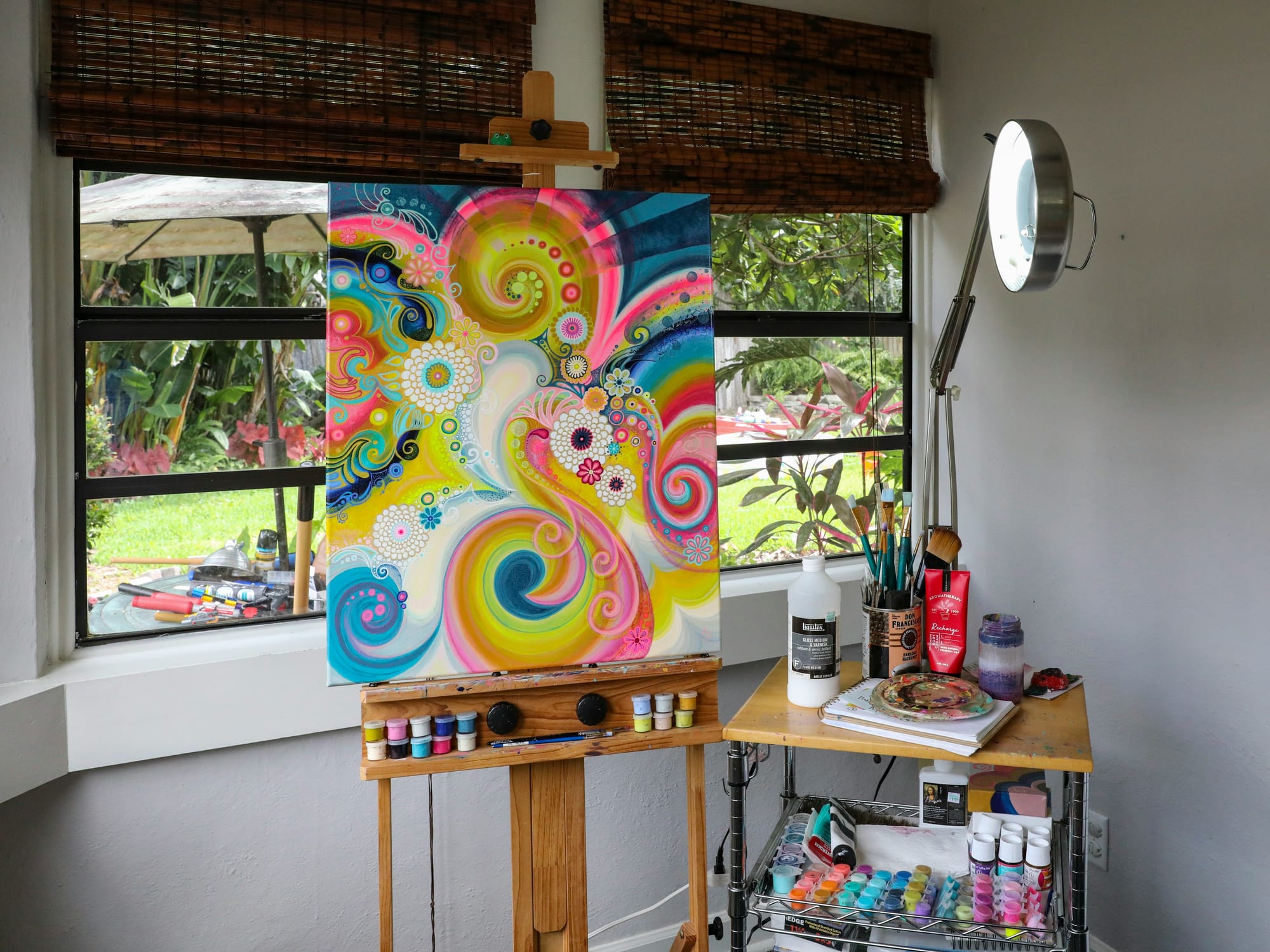 Close-up of an artist’s desk with sketchbooks, paints, digital tablet, and sculpting tools, representing the exploration of different art mediums.