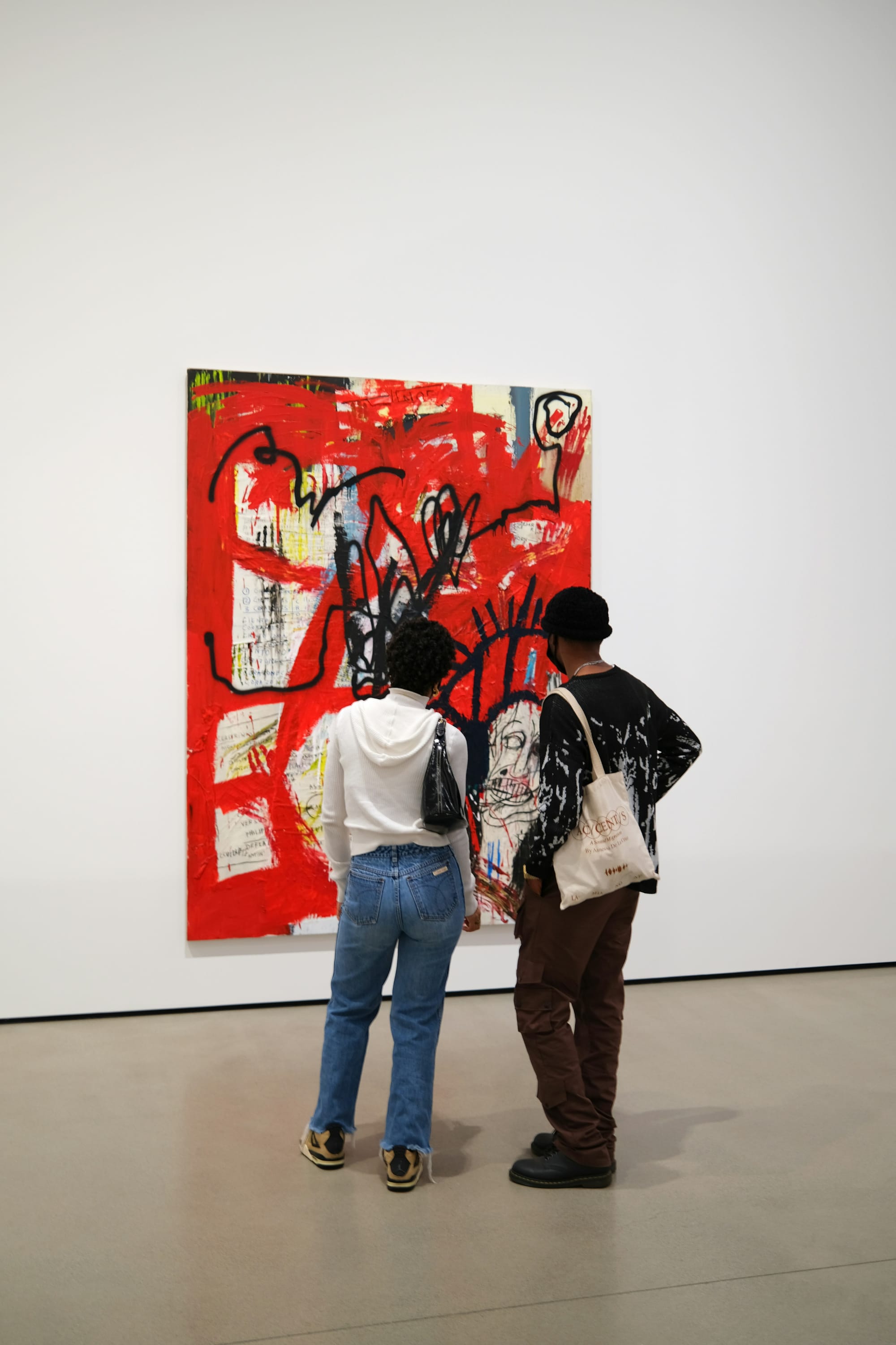 People standing close to a large abstract painting in a museum.