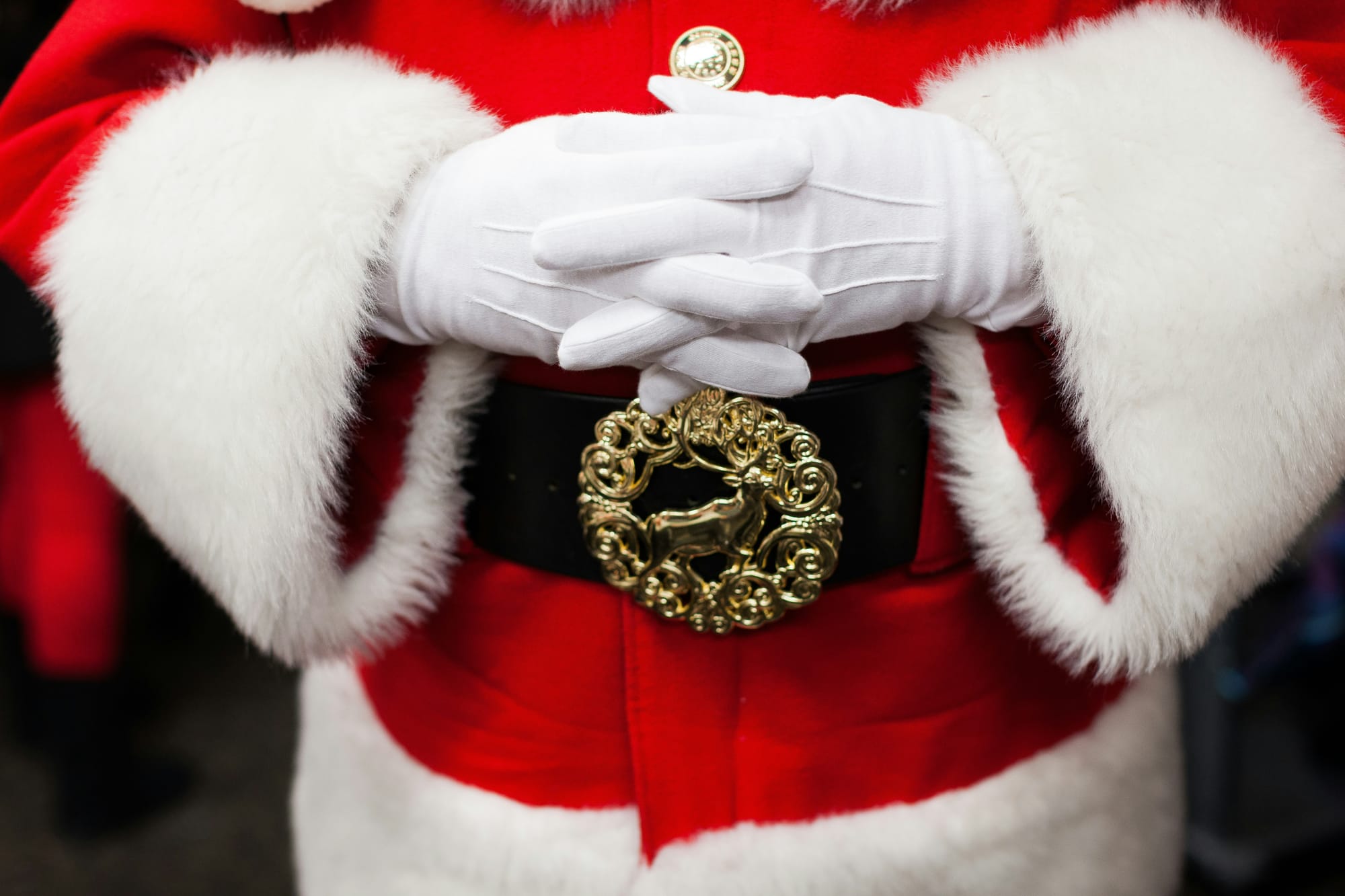 Close-up of Santa Claus’s hands in a red coat, symbolizing comfort, tradition, and the spirit of giving.