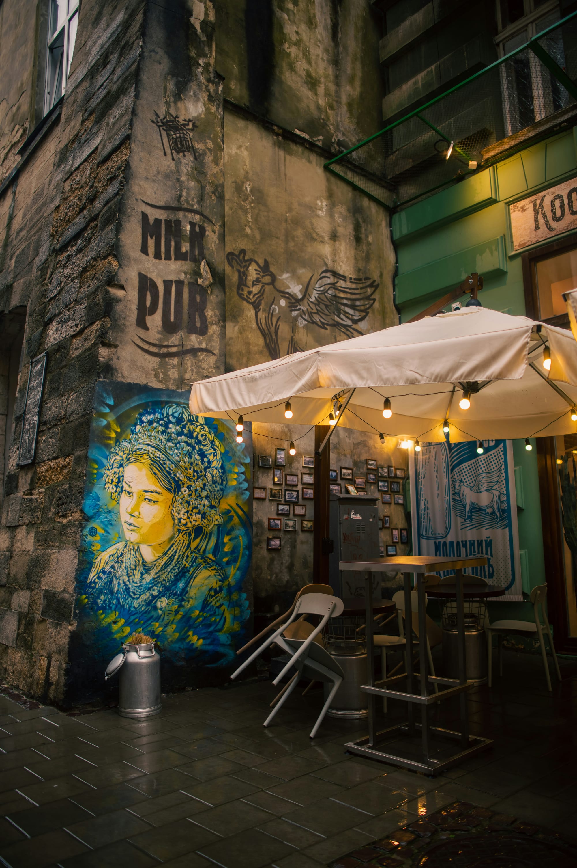 A small mural featuring colorful, whimsical designs on the wall of a quaint café, with a few tables and chairs in a warm, inviting setting.