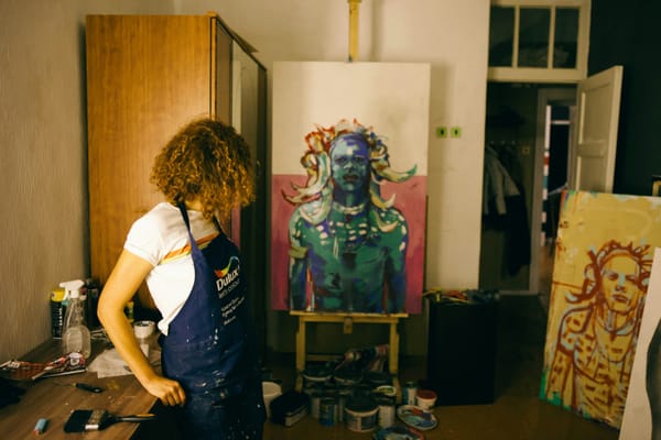 An artist sketching in their studio, surrounded by completed artworks, representing the emotional effort behind each piece.