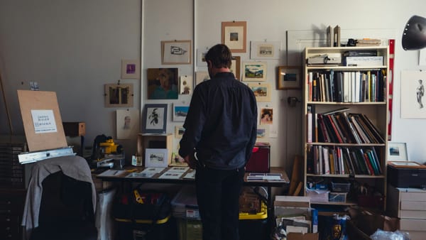 A struggling visual artist working in a studio with art supplies.