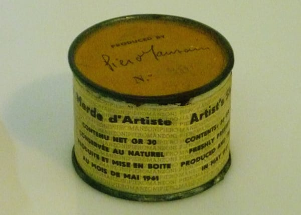 A close-up photograph of Piero Manzoni's Artist's Shit (1961), a steel can with multilingual labeling.