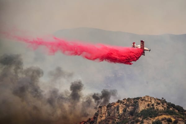 A firefighting plane releases fire retardant over raging flames in the Los Angeles hills.